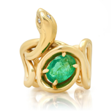 A gold snake ring with a large oval green emerald-cut center stone and small clear stones along the head, shown on a clean white background with a soft reflection.