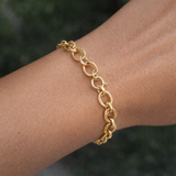 Gold chain bracelet on a wrist with a blurred natural background
