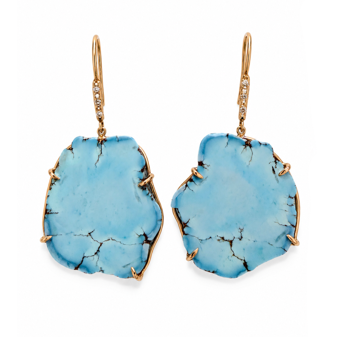 A pair of gold drop earrings featuring irregular, raw turquoise blue stone pendants with natural dark veining, suspended from gold hooks with small clear accent stones.
