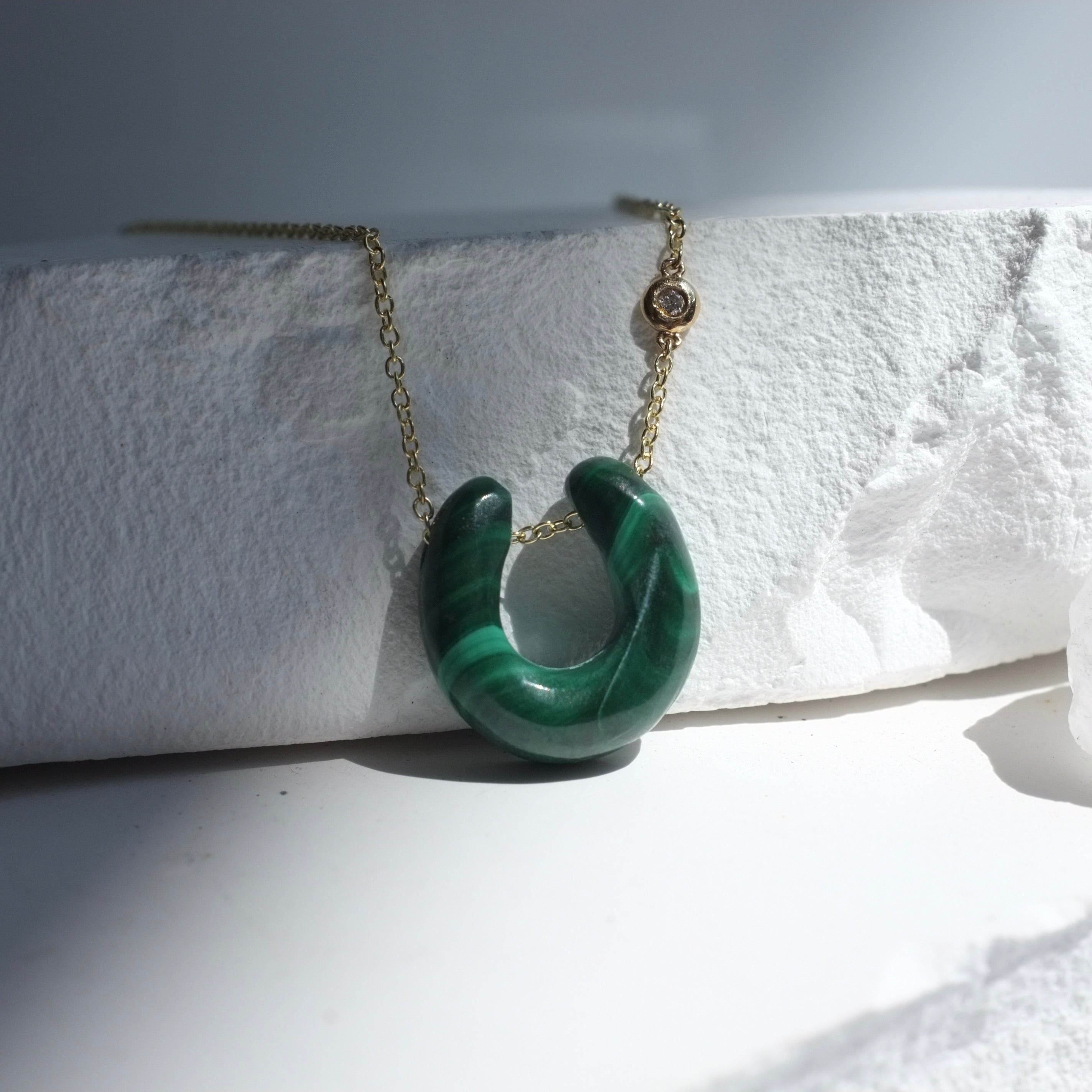 Green stone pendant necklace on a white surface