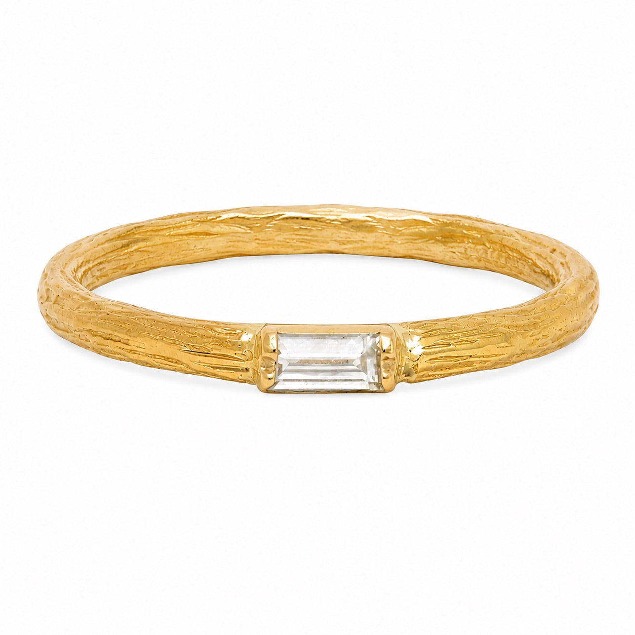 A textured yellow gold ring with a rectangular clear baguette-cut gemstone in the center, set against a plain white background.
