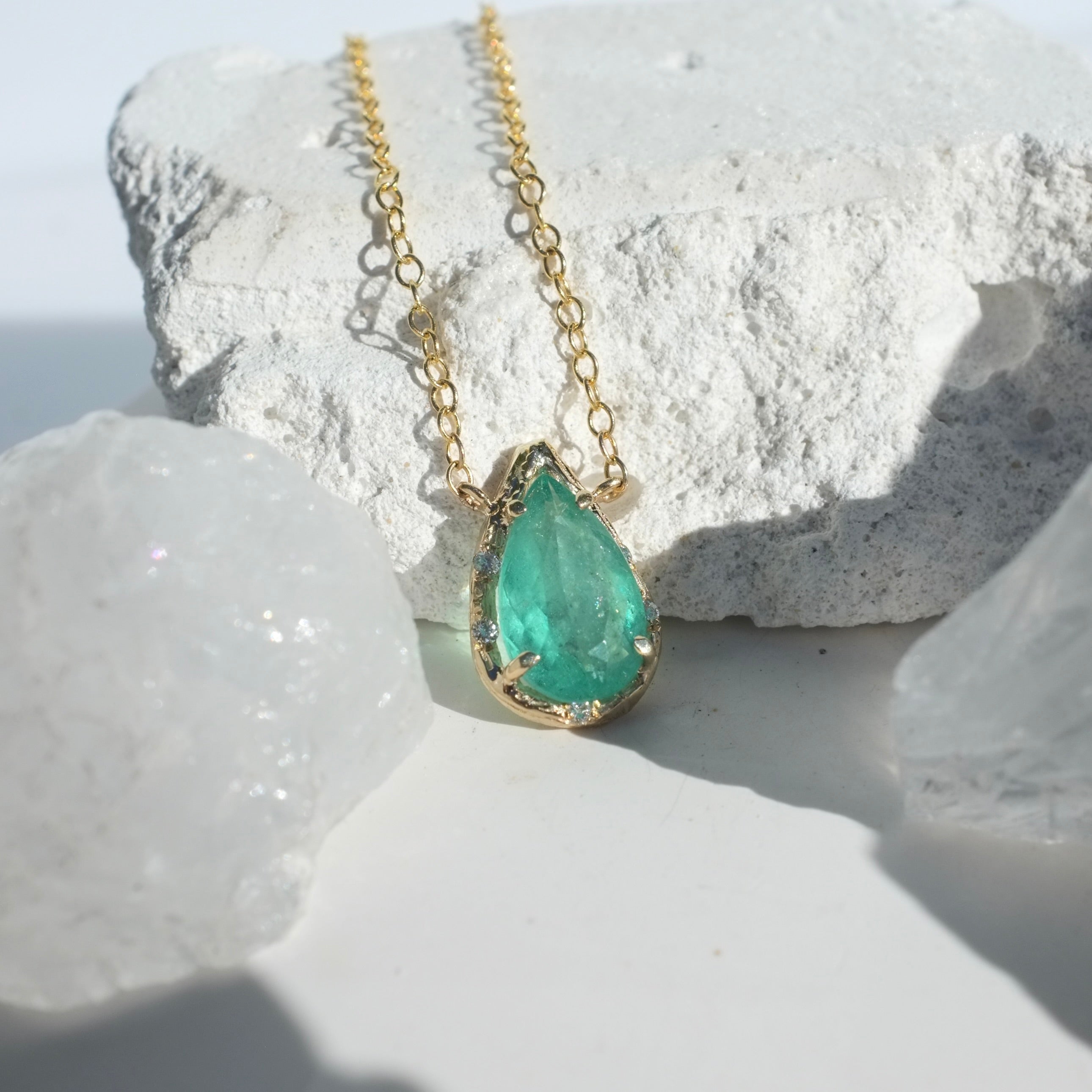 Brazilian Pear Emerald Willow Necklace photographed on a white background of rocks and crystals