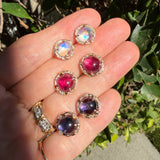 Iolite Pavé Round Stud Earrings side by side with other similiar studs in different gemstones on a hand