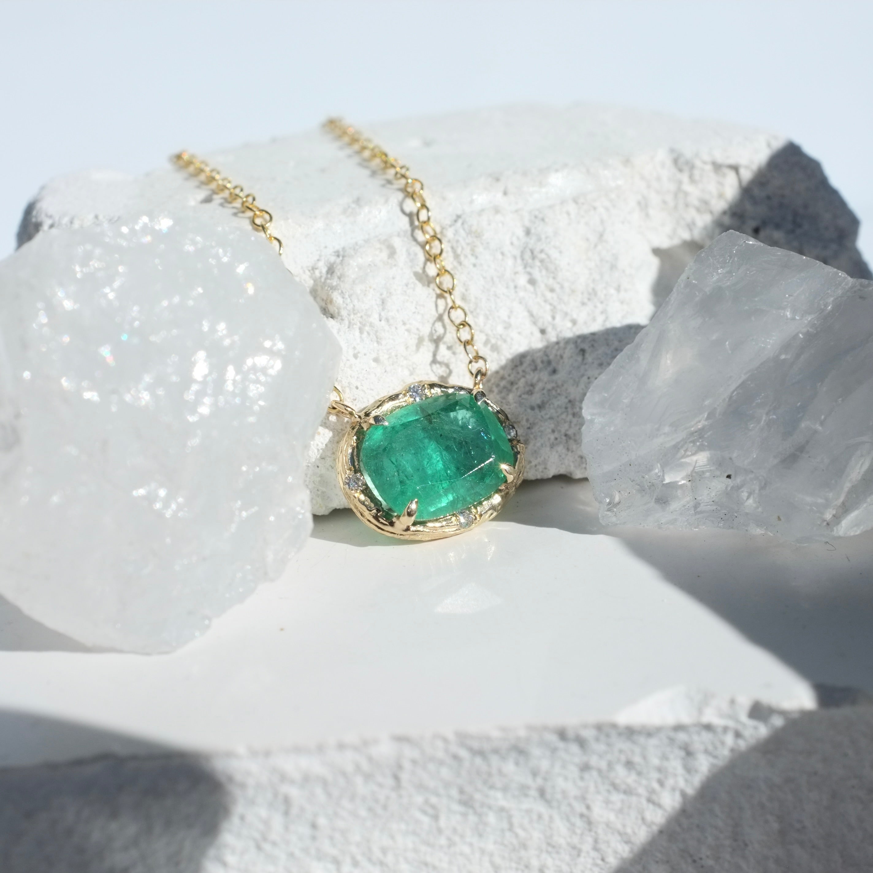 Zambian Cushion Emerald Willow Necklace photographed on a white background of rocks and crystals